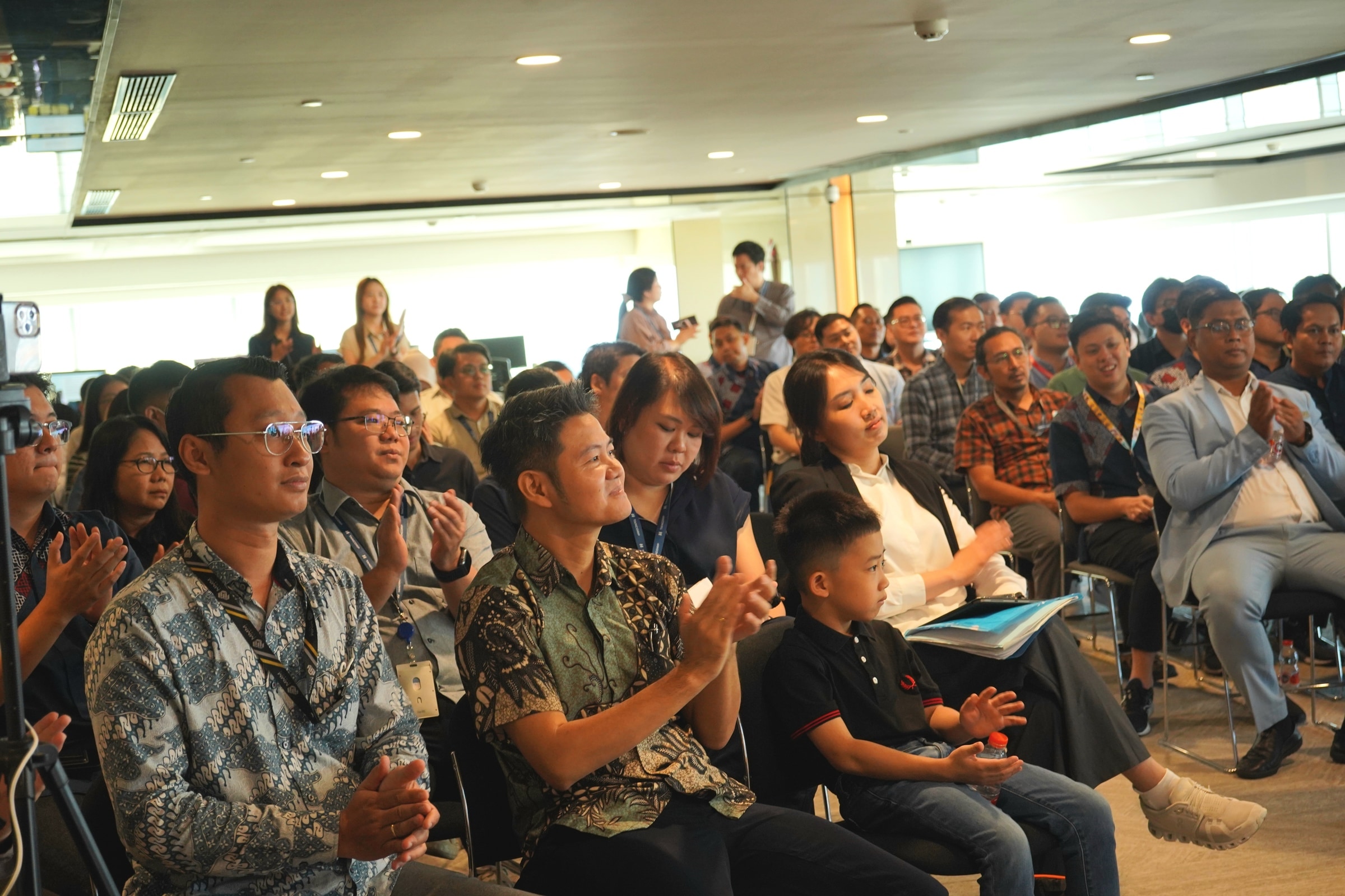 Olisiang seated among attendees in a large professional gathering.