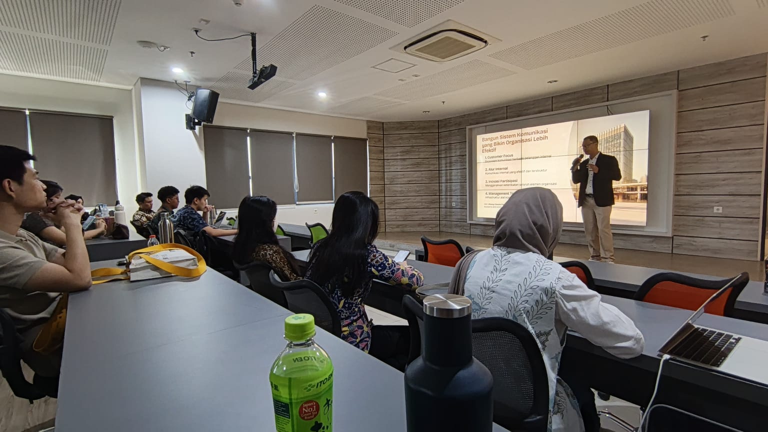 Olisiang presenting to attendees in a Universitas Ciputra classroom.